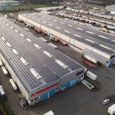 Zwei große Industriehallen aus der Vogelperspektive mit Photovoltaikanlagen auf den Dächern.